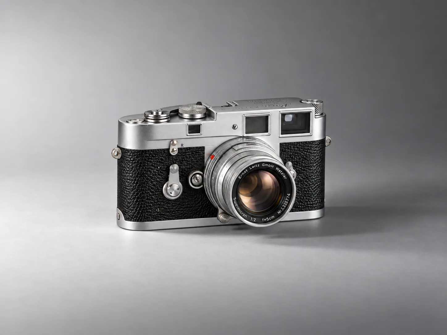 A silver and black rangefinder camera lit by a single studio key from the front, upper left.